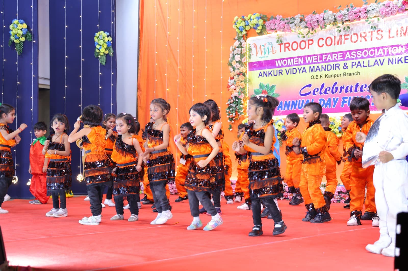 Children performing a dance routine in orange and black at the Annual Day